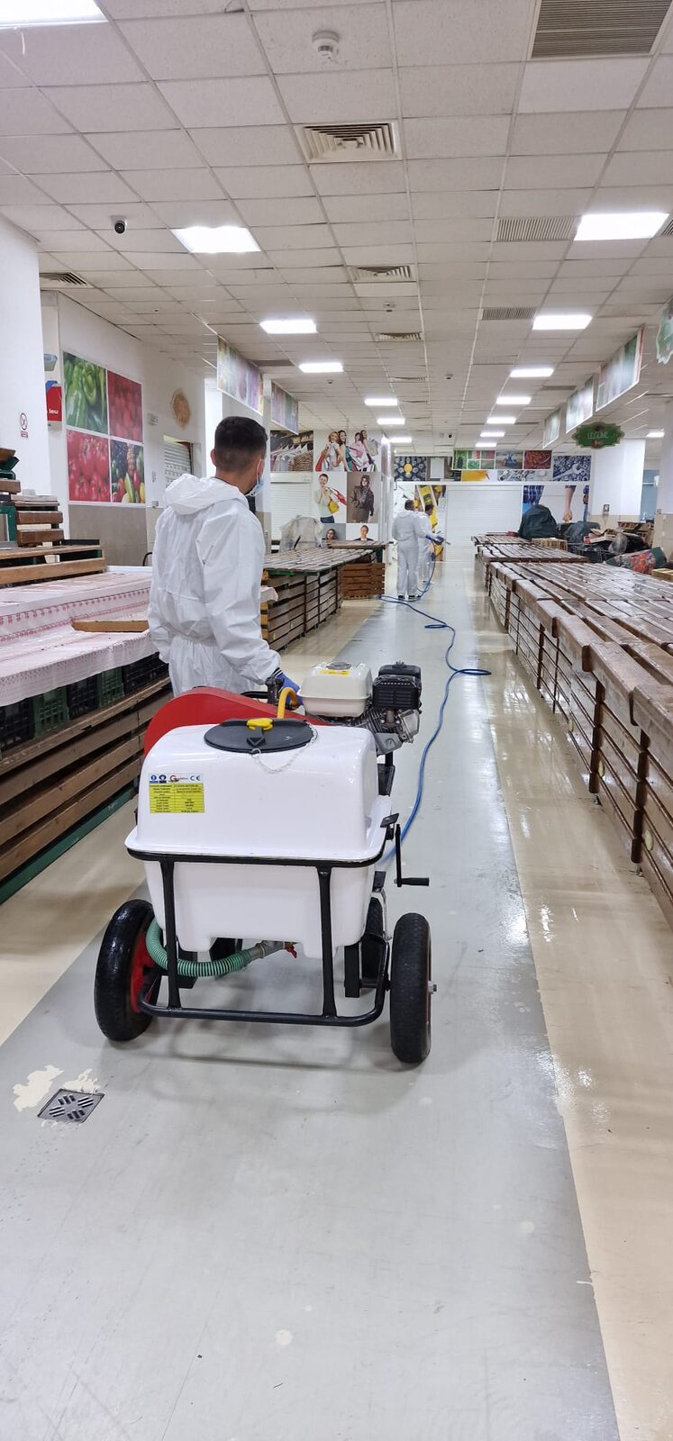Tehnician Eco-Bioterra în costum PPE complet folosind atomizor pe roți